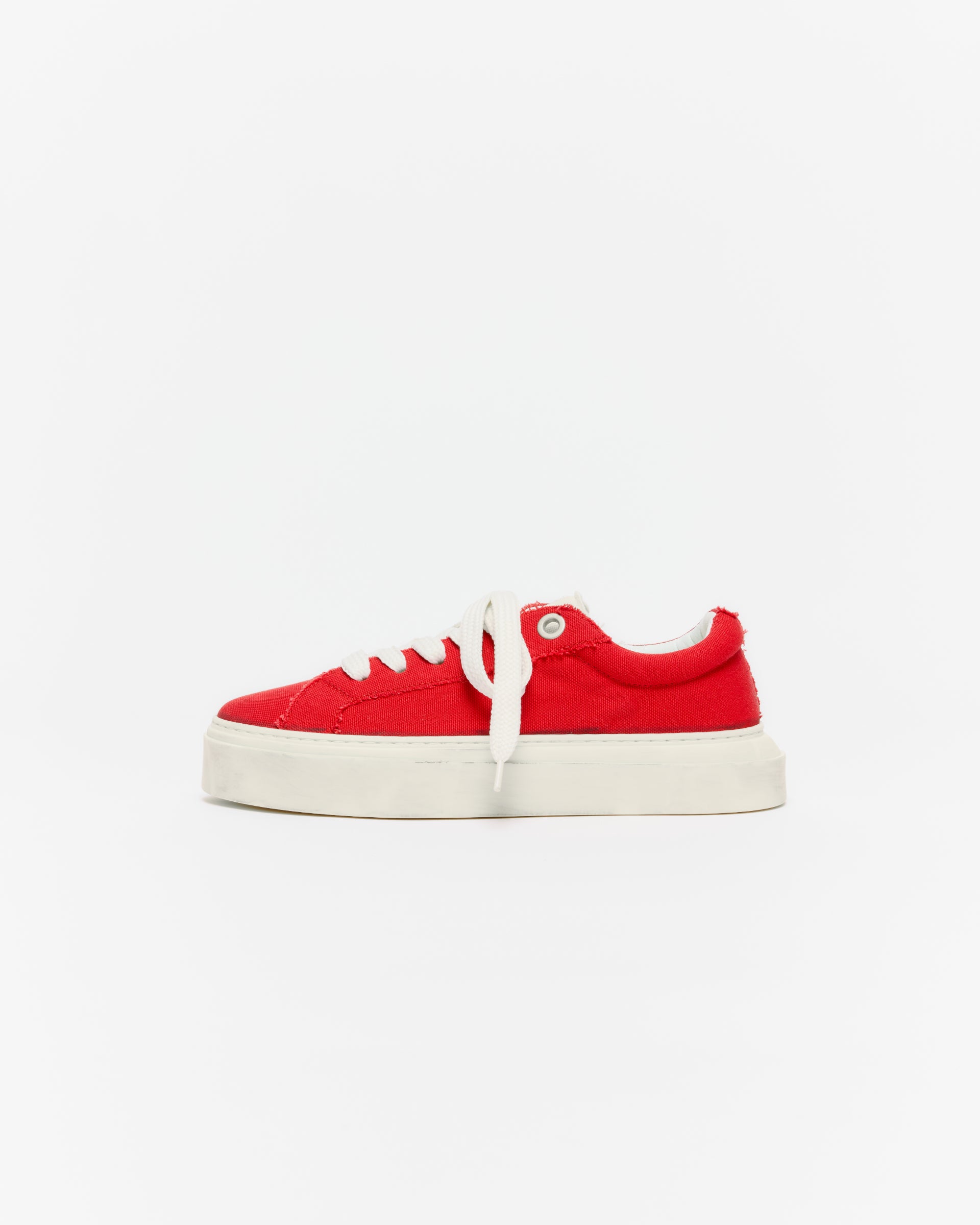 Red sneaker with white sole on a light gray background