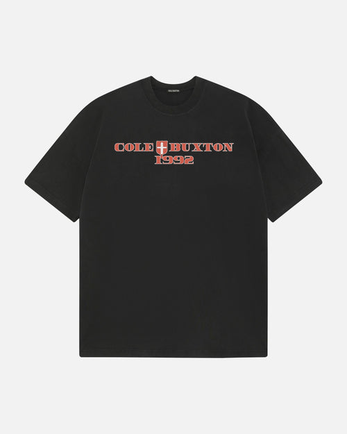 A black short-sleeve t-shirt with 'COLE X BUXTON 1992' printed across the chest in red and white, set against a light gray background.